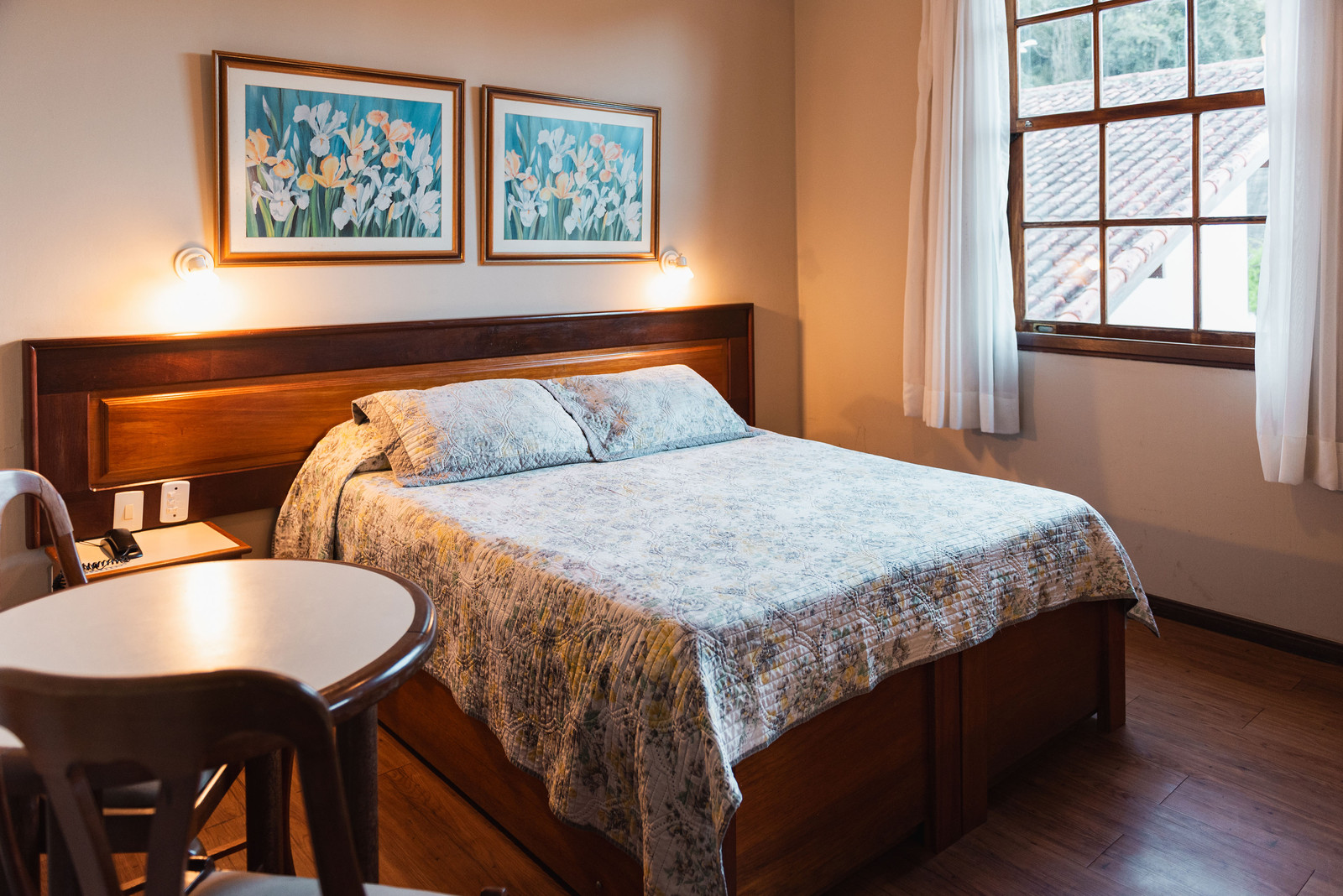 Quarto com cama de casal, quadros e mesa de apoio