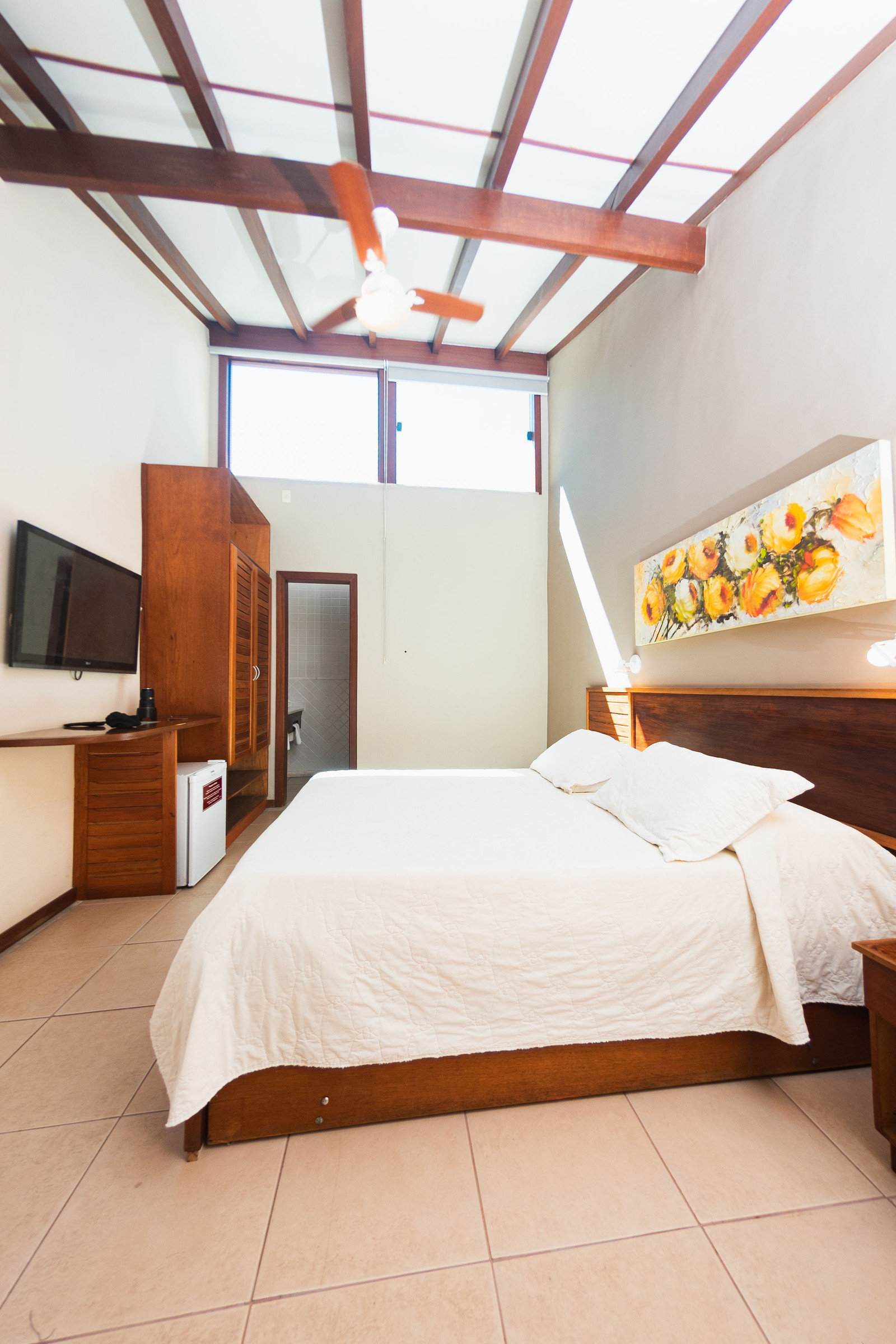 Quarto com teto de madeira, cama e TV