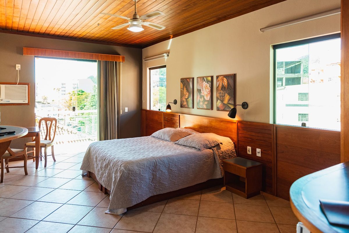 Suíte com Hidromassagem: cama, mesa de apoio e janelas